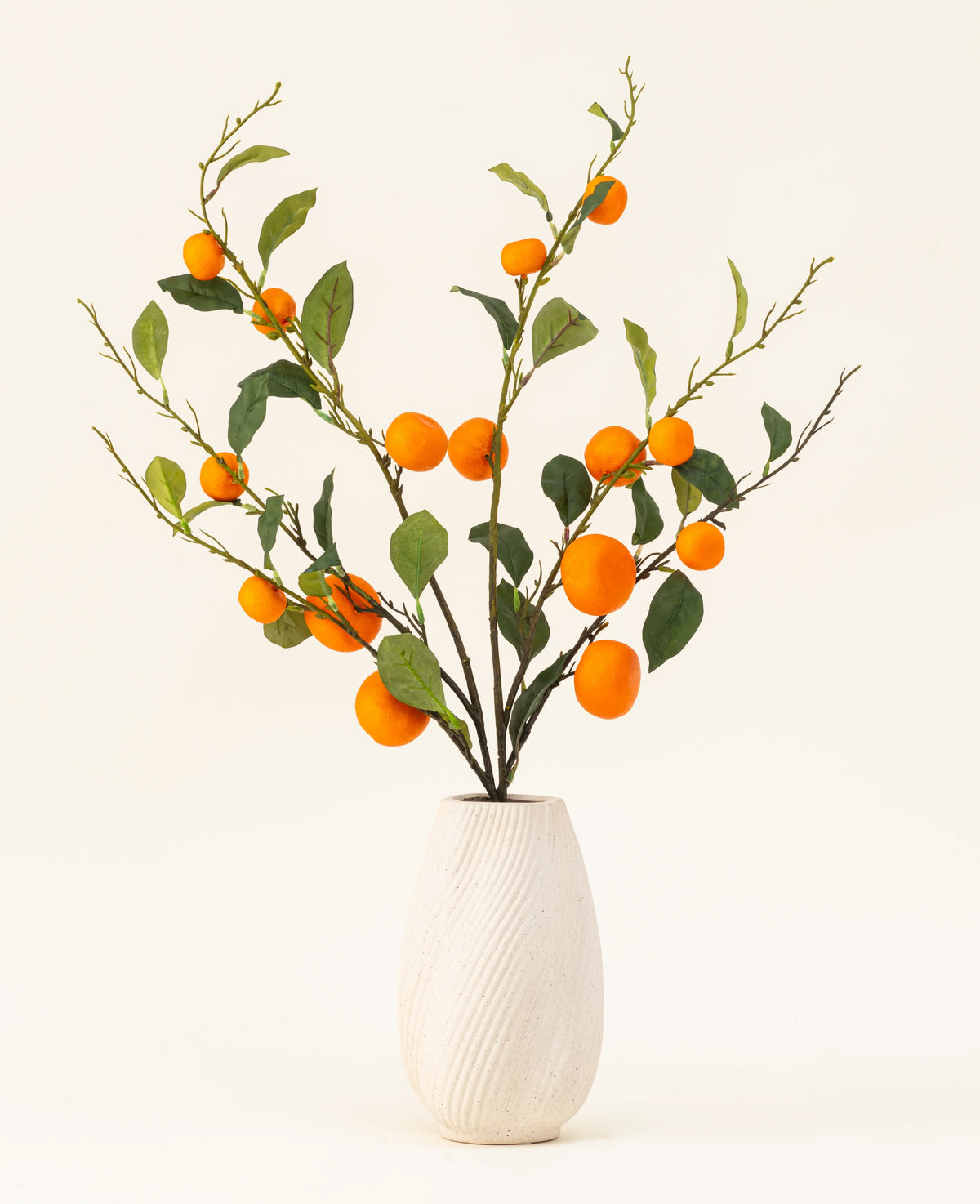 Der künstliche Blumenstrauß „Mandarin“ aus Seide besteht aus einer weißen, strukturierten Vase und Zweigen aus grünen Blättern und leuchtend orangefarbenen künstlichen Mandarinen, die vor einem schlichten, hellen Hintergrund eine lebendige Note verleihen.