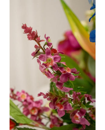 Nahaufnahme einer künstlichen Blumen-Katzenminze, 75 cm, rosa: eine Gruppe leuchtend rosafarbener künstlicher Blumen mit einem grünen Herzen und üppigen Blättern, scharf dargestellt vor einem sanft verschwommenen Hintergrund mit Andeutungen anderer Blumen.