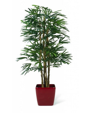 Die feuerhemmende Kunstpflanze „Lady Palm“ (180 cm) ist eine hohe künstliche Palme mit schlanken grünen Stielen und langen, schmalen Blättern, die in einem glänzend roten, quadratischen Pflanzgefäß vor einem weißen Hintergrund präsentiert wird.