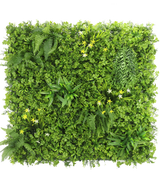 Die künstliche Hecke Narzisse Smile 100x100 cm UV ist eine quadratische vertikale grüne Wand mit dichtem grünem Blattwerk, Farnen und kleinen gelben und weißen Blüten vor einem weißen Hintergrund, von oben gesehen.
