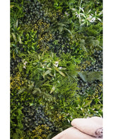 Eine üppige, strukturierte Kulisse wird durch die vertikale UV-Gartenwand Kunsthaag Freshness 100x100 cm geschaffen, die dicht mit grünem Blattwerk bedeckt ist. Unten rechts sind zwei gefaltete beige Handtücher zu sehen.